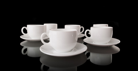 Obraz na płótnie Canvas White cups and saucers on a black background