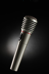 Shiny grey iron microphone on black background