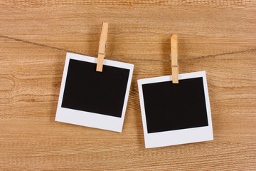 Photo papers hanging on the clothesline on wooden background