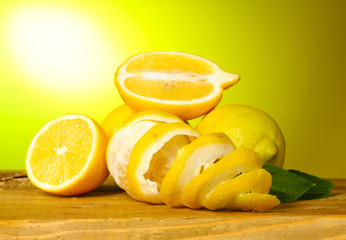 Fototapeta na wymiar ripe lemons with leaves on wooden table on green background