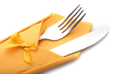 Fork and knife in a yellow cloth with a bow isolated on white