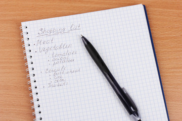 Shoping list and pen on wooden table