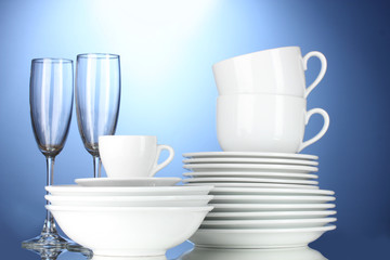 empty bowls, plates, cups and glasses on blue background