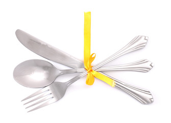 Silver fork and spoon, knife tied with a yellow ribbon isolated