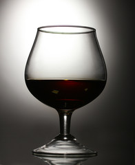 Glass of cognac on grey background