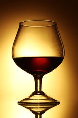Glass of cognac on yellow background