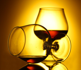 Two glasses of cognac on yellow background