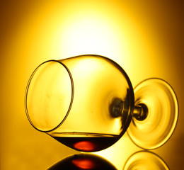 Glass of cognac on yellow background