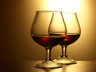 Two glasses of cognac on yellow background