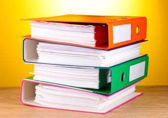 bright office folders on wooden table on yellow background.