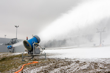 Snow cannon making snow on a ski slope - 38191599