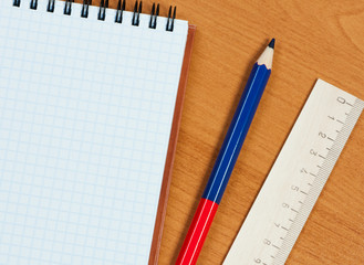 Pad, wooden ruler and pencil on table.