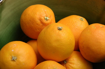 Some oranges fruits  in a green earthenware bowl.