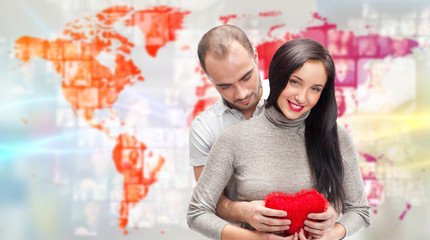 Portrait of young couple embracing and holding red heart. Standi