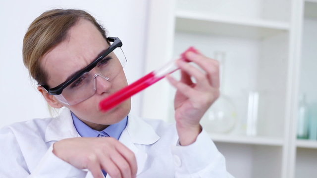 Female scientist analyzing test tube with red substance