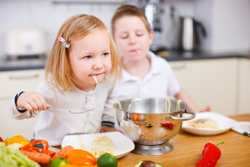 Two kids eating spaghetti