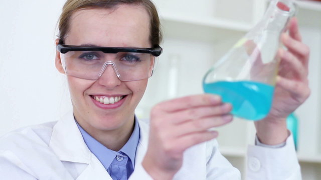 scientist mixing erlenmeyer flask with chemicals and smiling