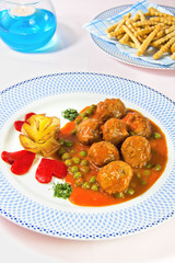 Bodegón de albóndigas en salsa con guisantes.