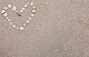Fototapeta na wymiar Heart made from shells in the sand background