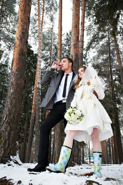 Bride and groom with champagne glasses in winter forest