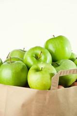 Fresh green apples in a grocery bag, over white background