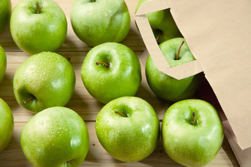 Paper bag and green apples lying on wooden boards, studio shot