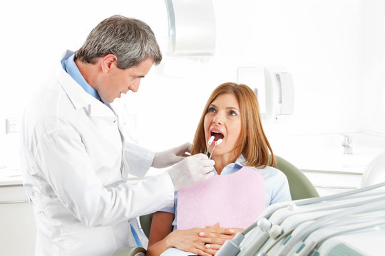 Zahnarzt mit Watterollen bei Patientin