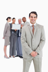 Smiling businessman with team behind him