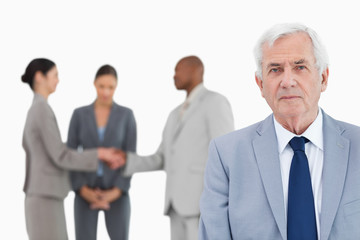 Mature businessman with trading partners behind him