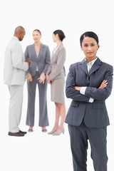 Confident saleswoman with negotiating trading partners behind he