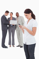 Saleswoman with mobile phone and colleagues behind her