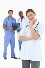 Doctor in thinkers pose with colleagues behind her