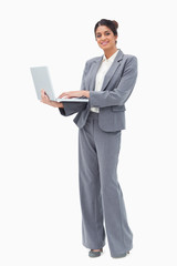 Smiling businesswoman using laptop while standing