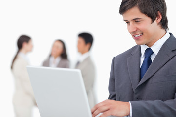 Obraz premium Salesman with laptop and colleagues behind him