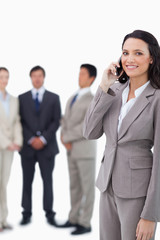 Smiling saleswoman on cellphone with team behind her