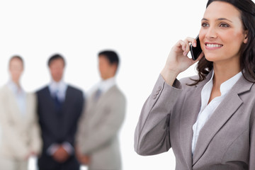 Smiling saleswoman on her mobile phone with team behind her