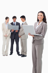 Smiling saleswoman with laptop and associates behind her