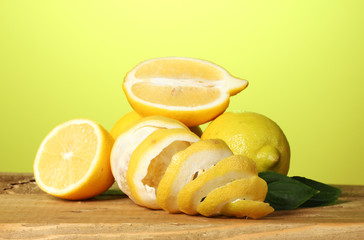 ripe lemons with leaves on wooden table on green background