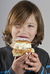 Young boy with a cream bun with almond paste
