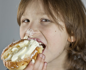 Boy enjoying a cream bun with almond paste