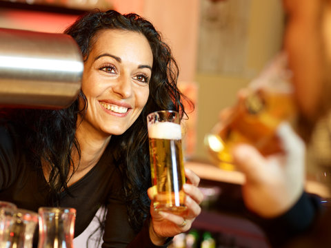 Pretty lady bartender with a glass of beer has fun at work
