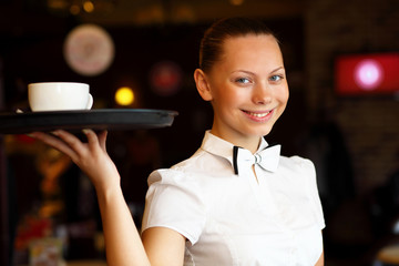 Portrait of young waitress holding a tray