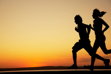Young couple run together on a sunset