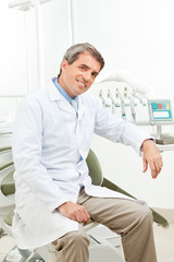 Zahnarzt sitzt auf Behandlungsstuhl