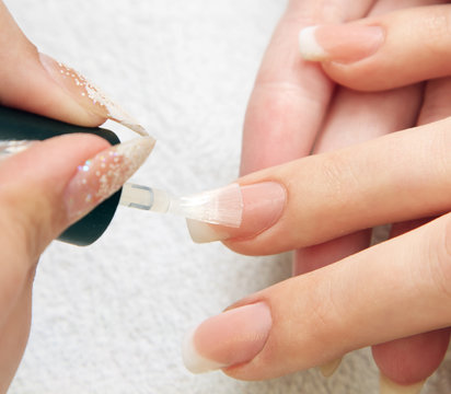 manicure making - female hands, covering of transparent enamel