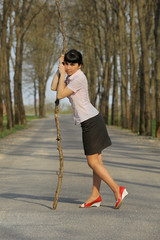 Meditative girl standing with a stick on a road