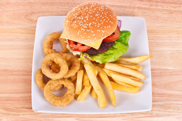 Cheeseburger with chips and onion rings on the plate