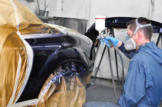 Worker painting a car.