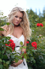 blond woman standing in rose's garden
