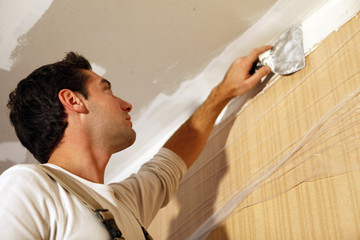 Man putting up a plasterboard ceiling